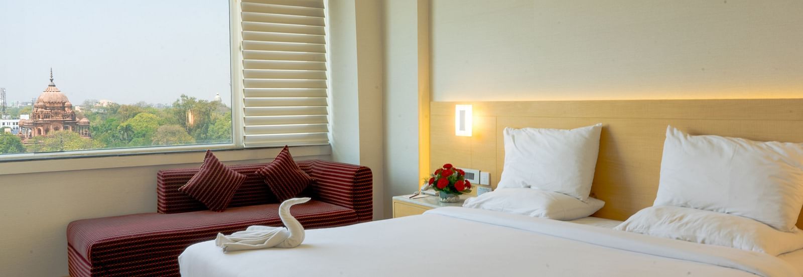 Side-angle of a room featuring a double bed and seating area with natural light streaming in | Gemini Continental