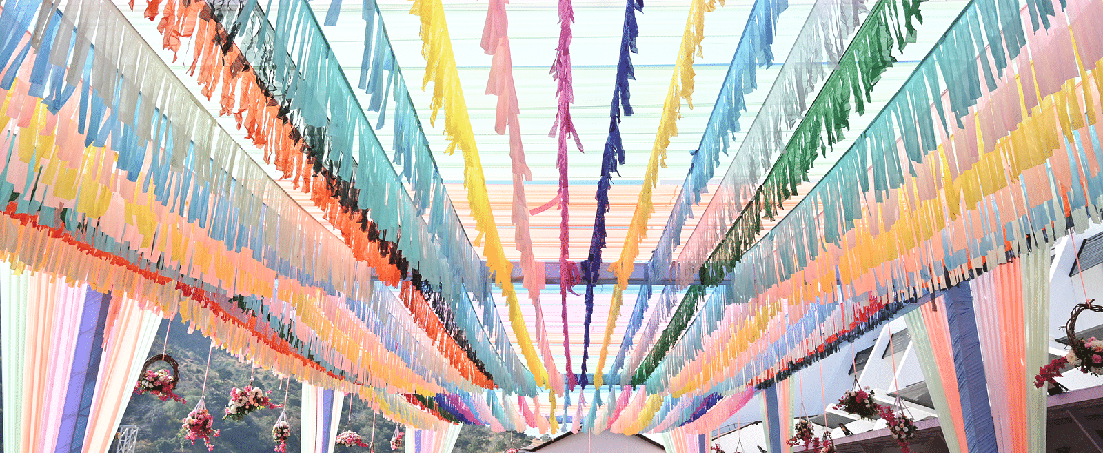 Colourful ribbons strung overhead with people gathered below - Via Lakhela Resort & Spa