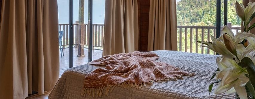 An image of a bedroom with king size bed, frames on the wall, a dressing table, a cabinet at Avalon Cottages, Kanatal