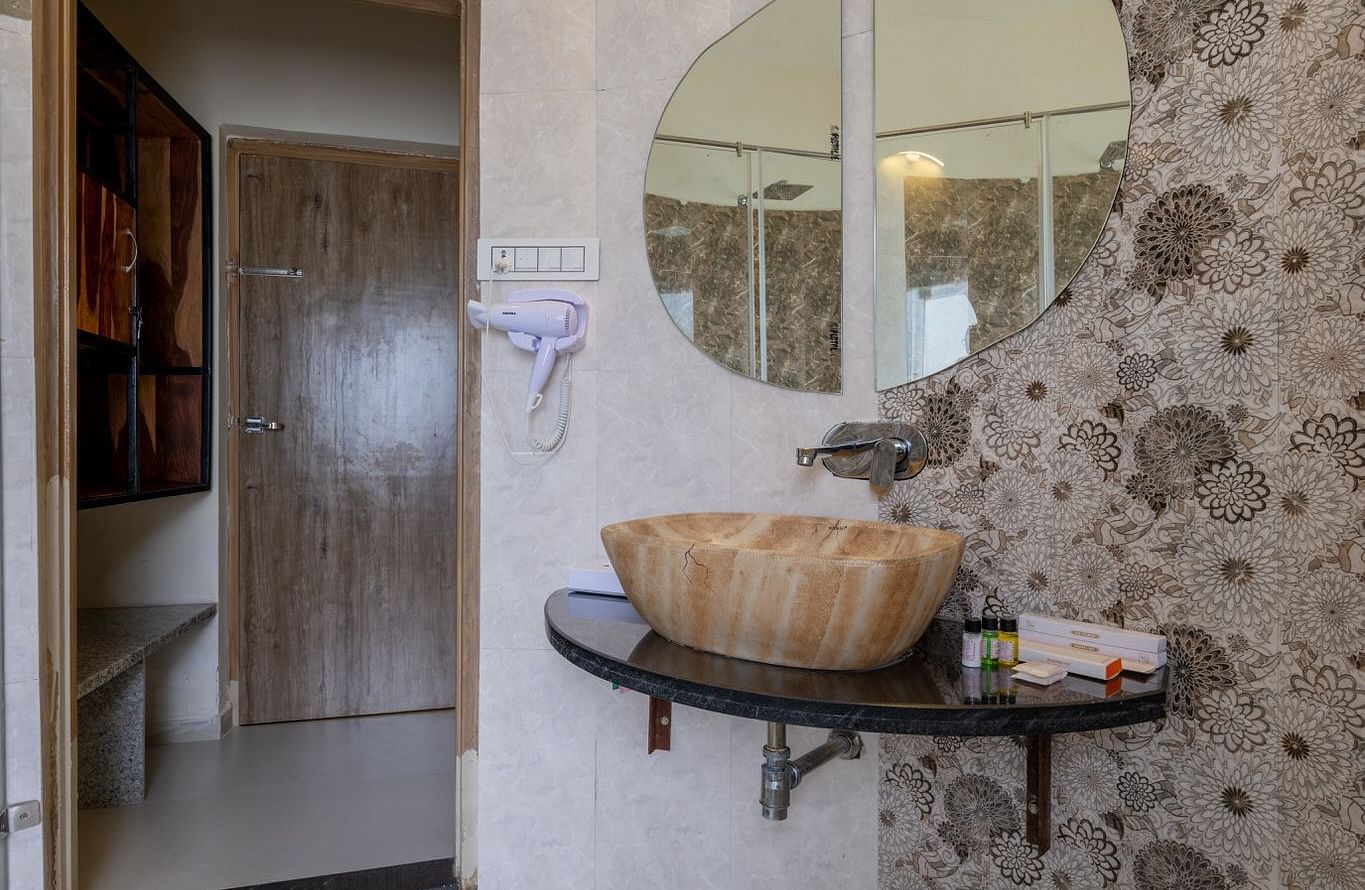 A mirror mounted above a sink with an open door on the side at Valley by Grassfield.
