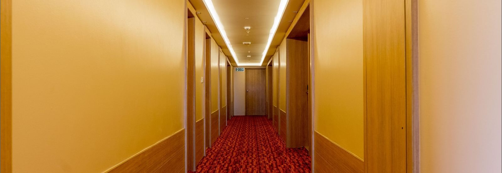 Long, well-lit corridor in a hotel with a red carpet | Gemini Continental