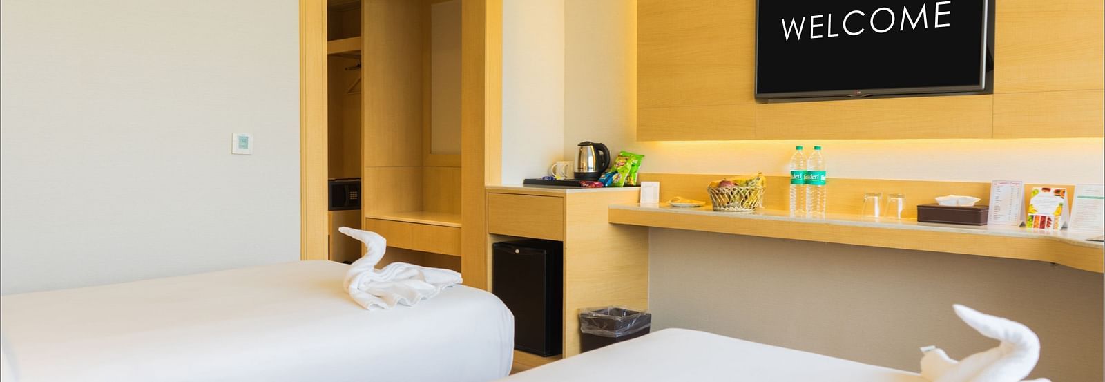 Twin beds with white linens in a room that has a desk and wall-mounted TV | Gemini Continental