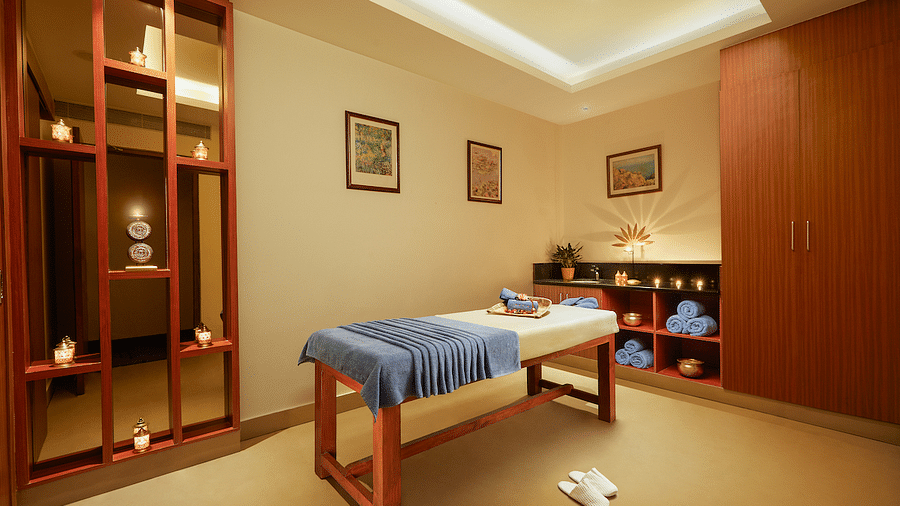 Spa room with a massage table, folded cloth, red partition, and storage cabinets - Karur 