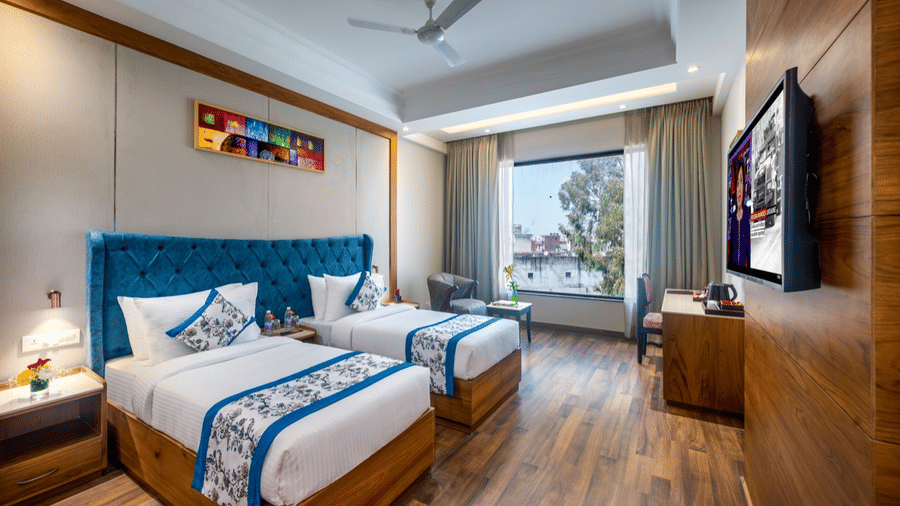 Brightly lit Sup Twin room with two twin beds, blue-themed bedding, large windows, and modern furniture.