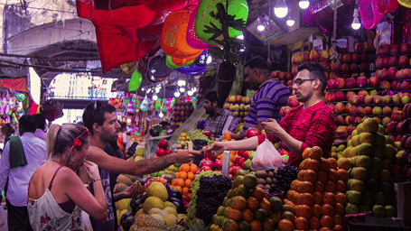 People buying fruits from the fruit seller in a market.