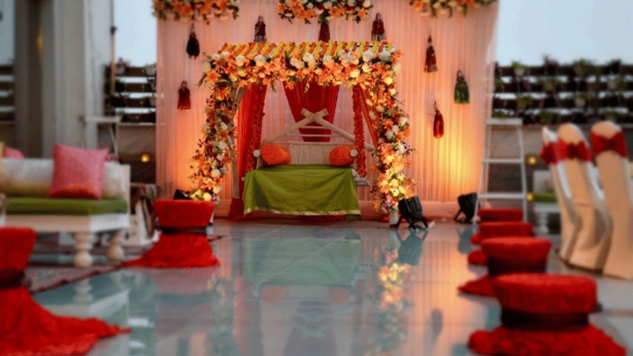Elegant wedding mandap setup at Ramada Plaza by Wyndham Palm Grove, featuring floral decor, warm lighting, and floor seating arranged along a reflective aisle.