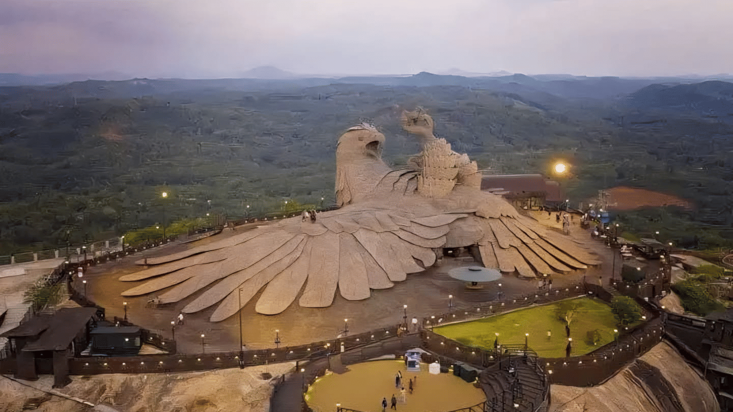 The massive, detailed Jatayu sculpture atop a hill in the Jatayu Earth's Center, surrounded by lush green landscapes at dusk.