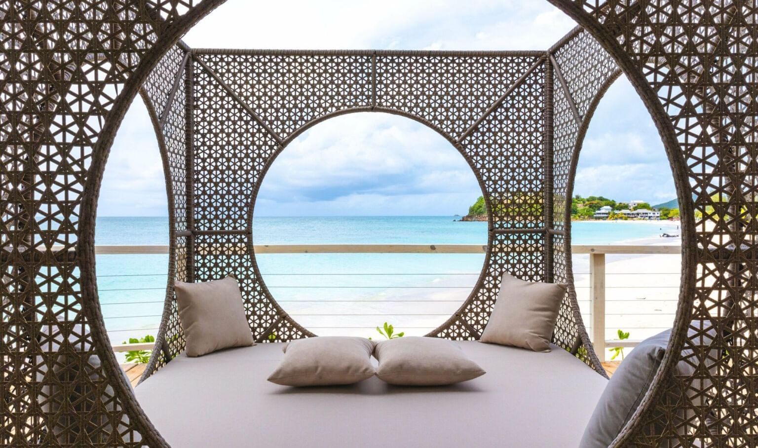 A decorative, circular outdoor daybed with intricate patterns at the Tamarind Hills Resort and Villas - Antigua, offering a view of the beach, and sea.