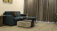 A modern space with a couch and curtains and bright lighting.- Golden Suites, Gurgaon