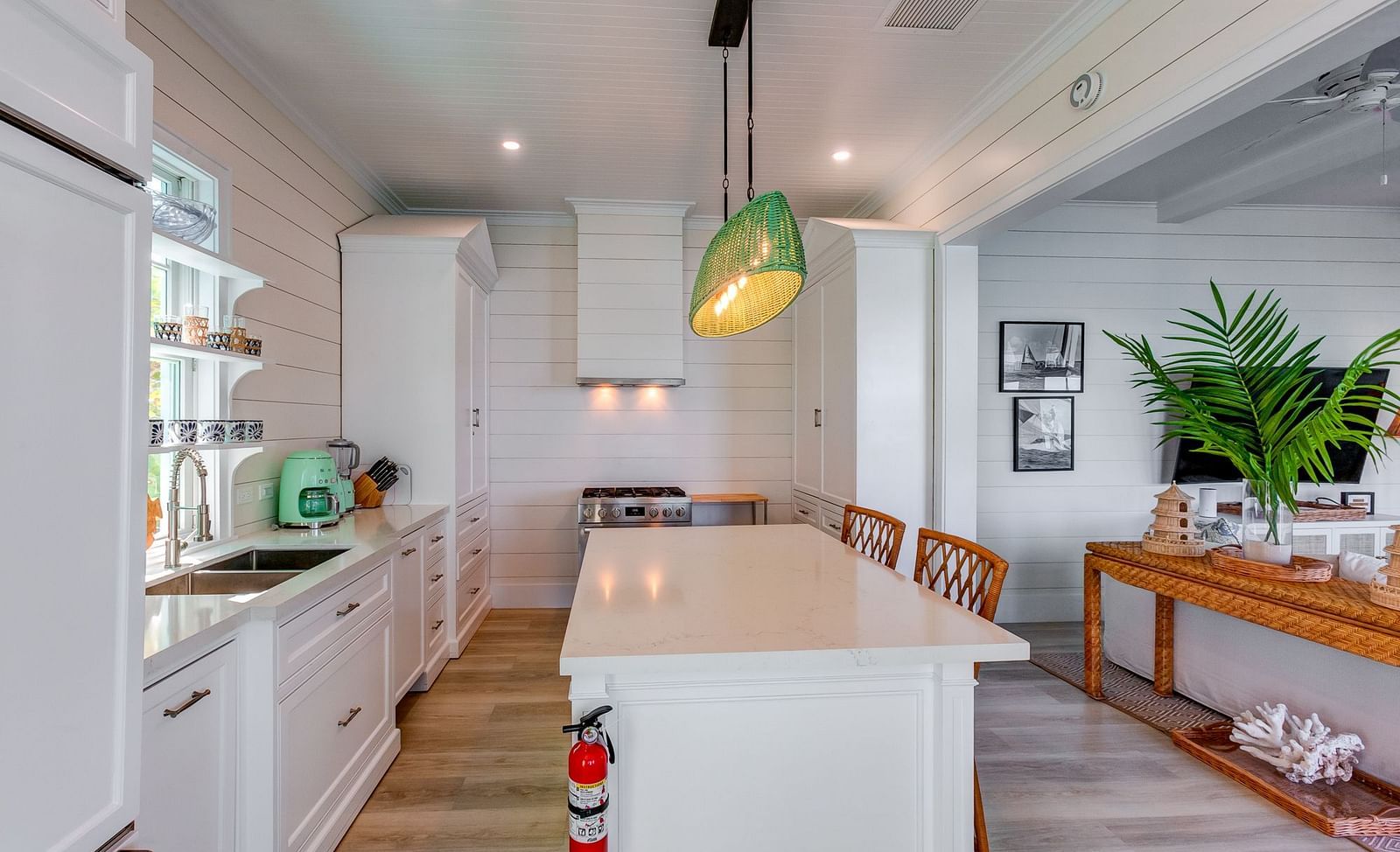 Modern kitchen with white cabinetry, wooden stools, and green pendant light | Abaco Inn
