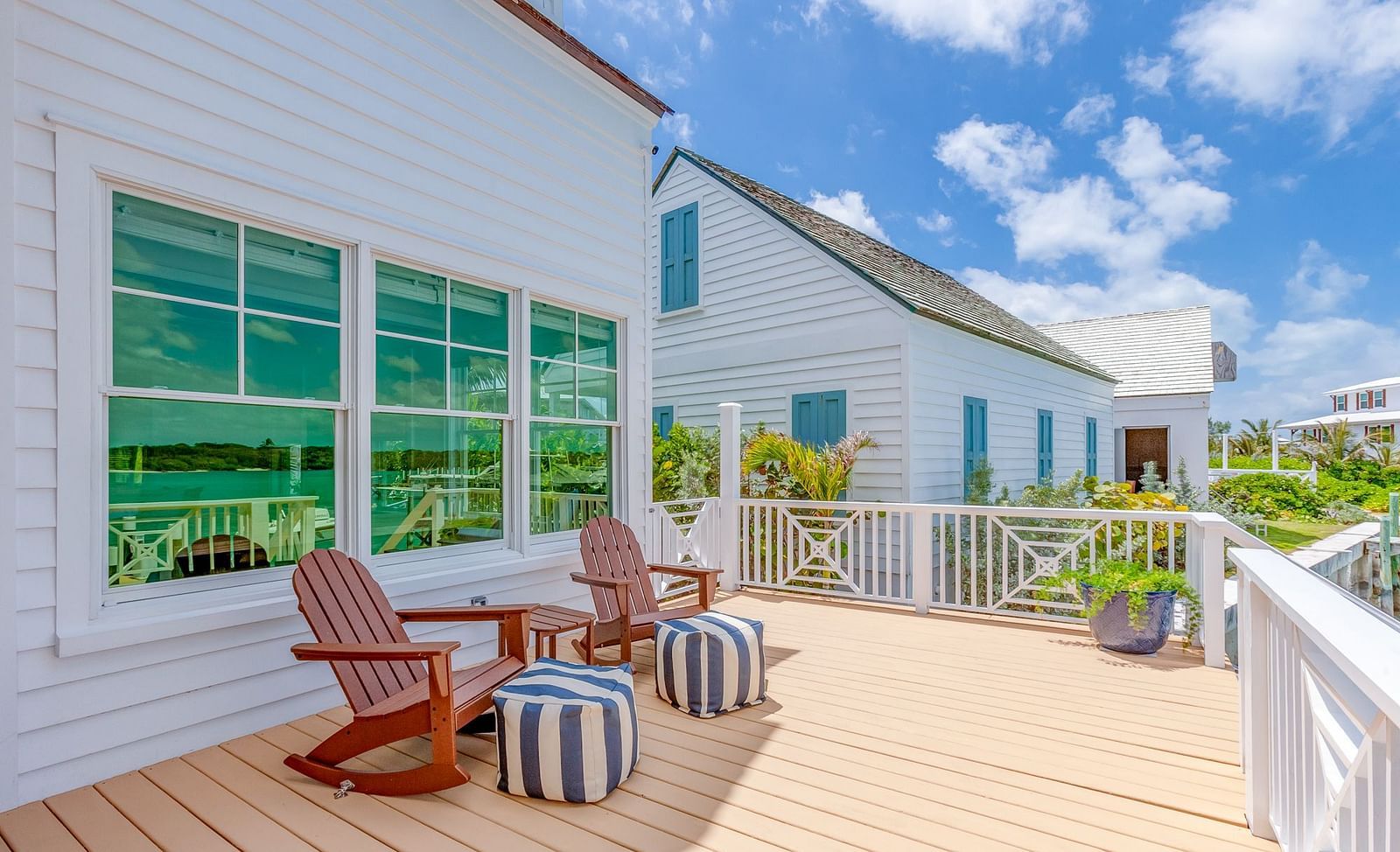 Wooden deck with Adirondack chairs outside a white coastal-style building with green shutters | Abaco Inn