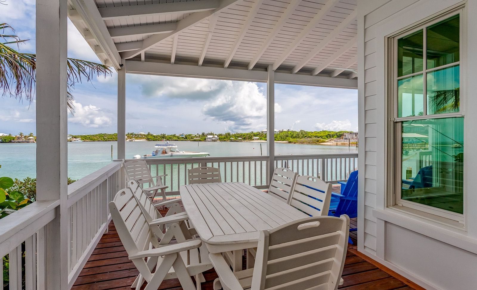 Spacious deck with a dining table and lounge chairs overlooking the water | Abaco Inn
