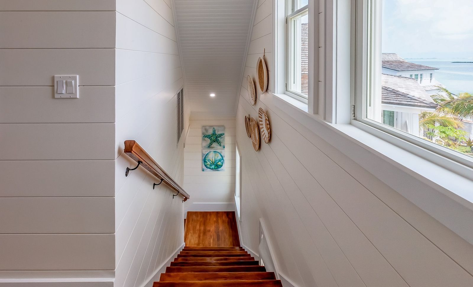 stairways at Abaco Inn with white walls, wall decors and windows with the sea view  .