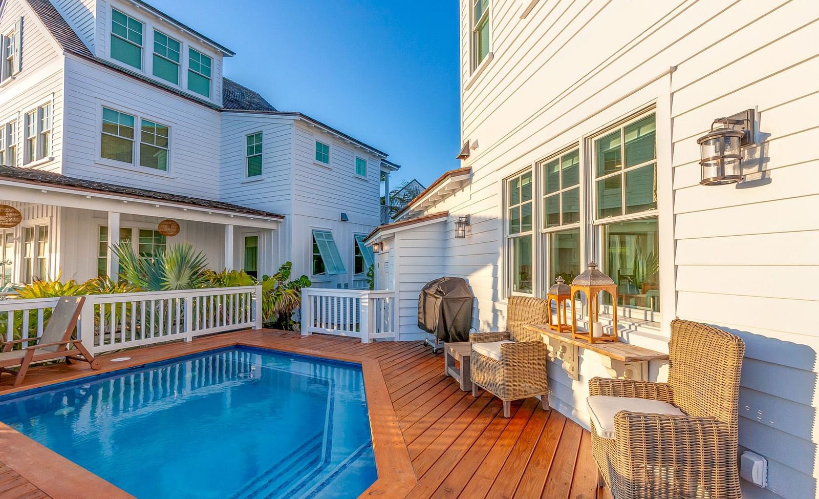 a swimming pool and two houses on a dock with wooden chairs at Abaco Inn.