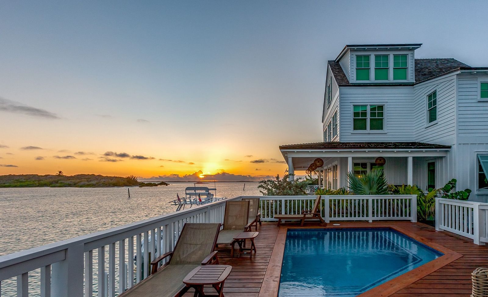 Swimming pool on a wooden dock with chairs, and the sea view with a sunset at Abaco Inn.