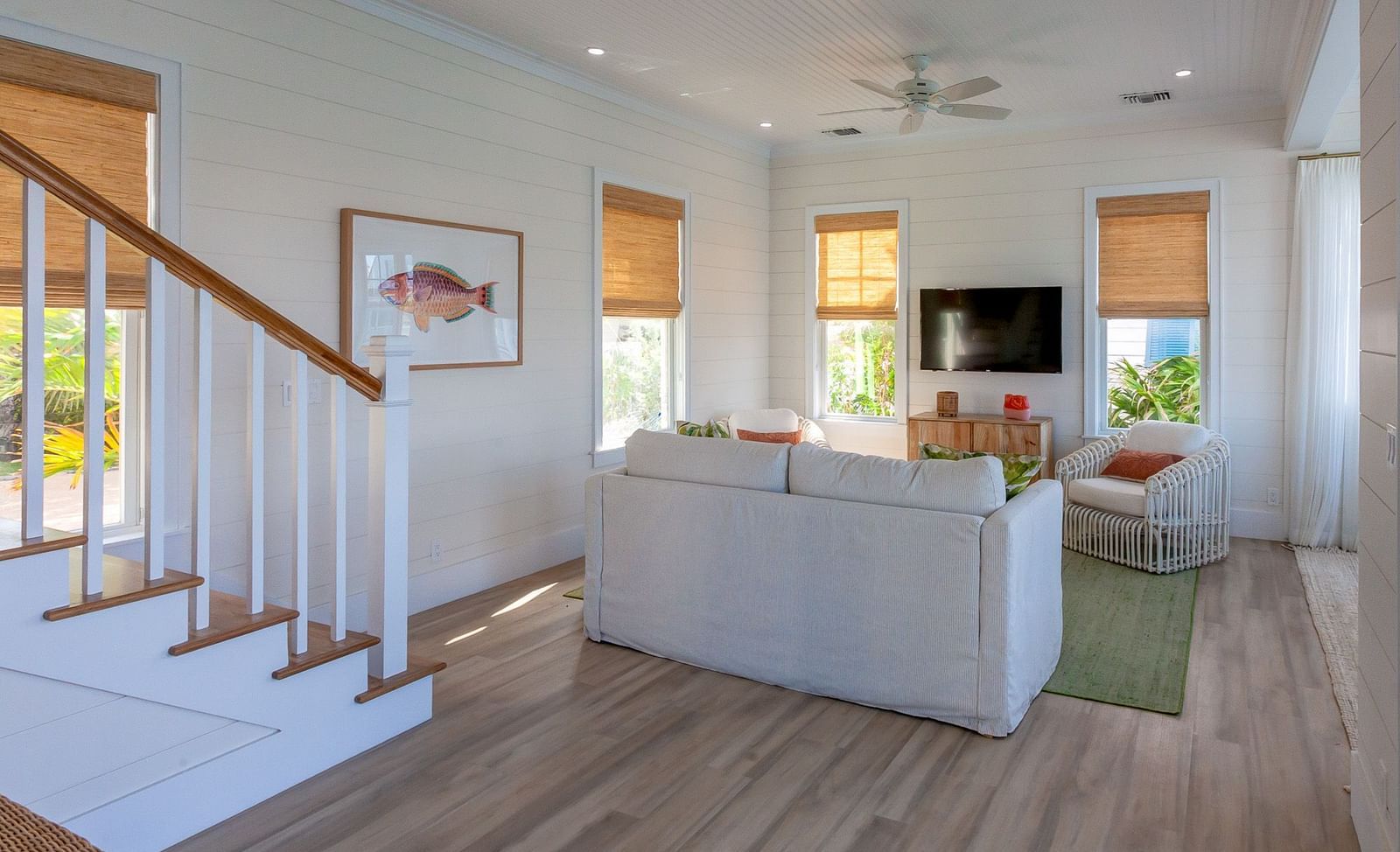 sitting area at abaco inn with sofa, TV, wall decors, and stairways.