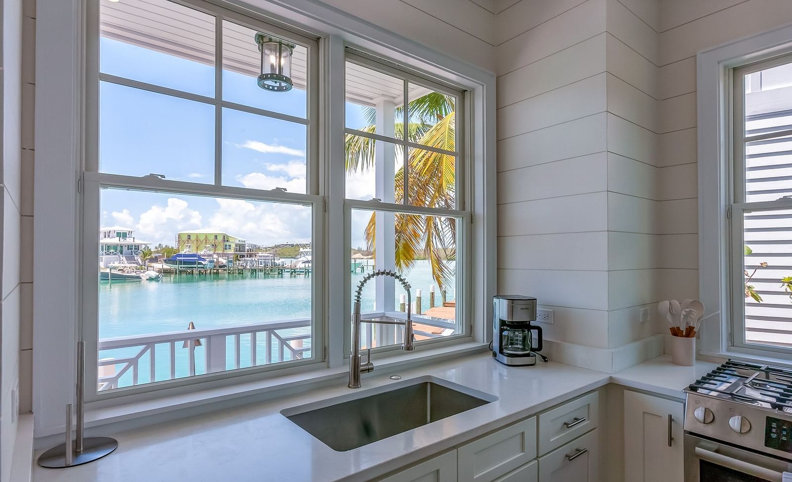 Bright and airy kitchen with a sink, cupboards, oven, and a window overlooking the sea at Abaco Inn.