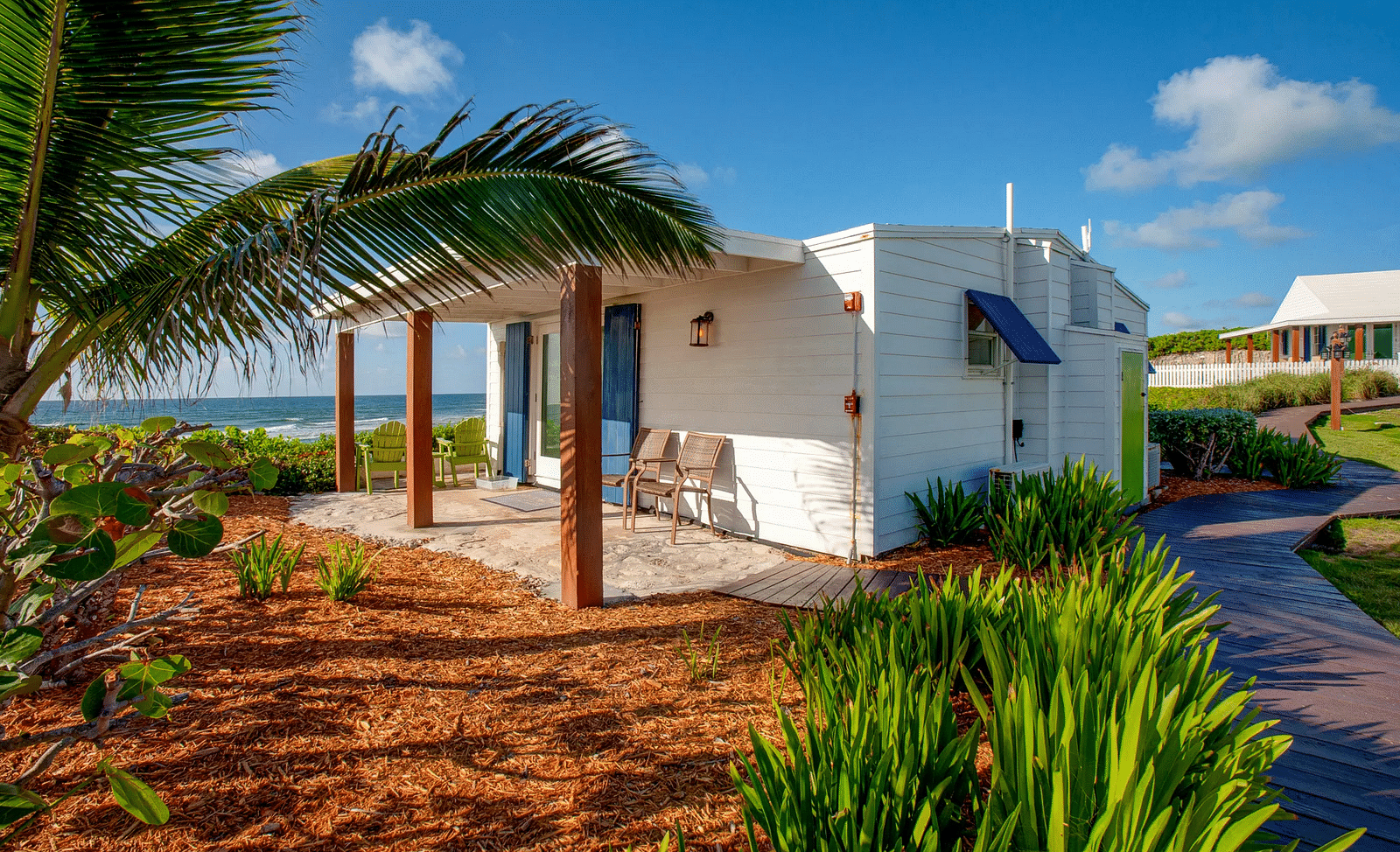 Small villa with pathway and tropical plants under a clear sky | Abaco Inn