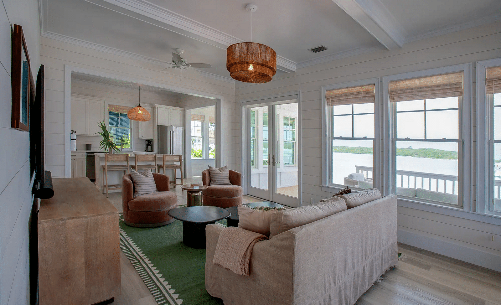 Living room with a beige sofa, green accents, and large windows | Abaco Inn