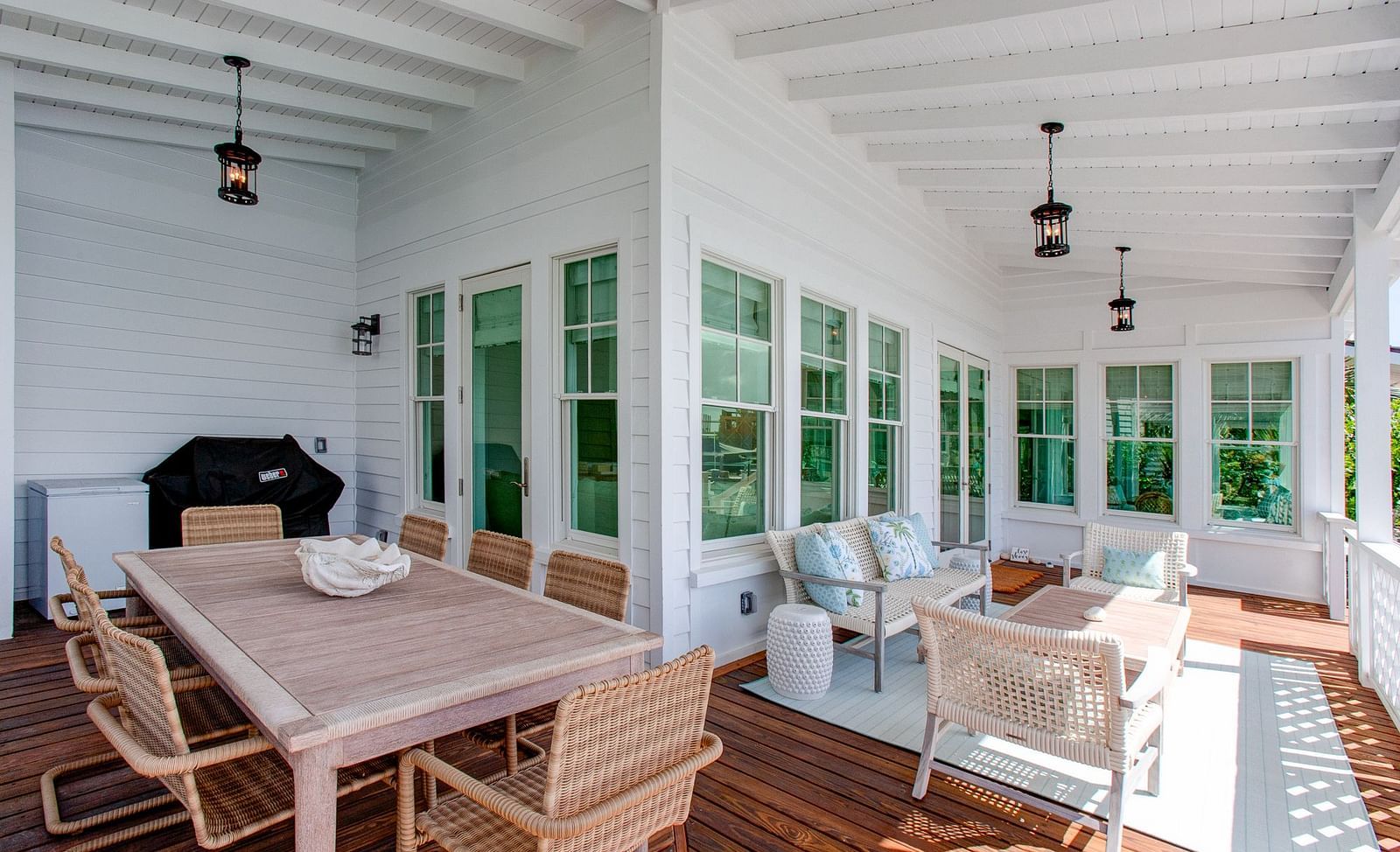 A spacious, sunlit room with extensive windows and light-toned walls at Abaco Inn, featuring a wooden dining table and chairs, along with various comfortable seating arrangements 