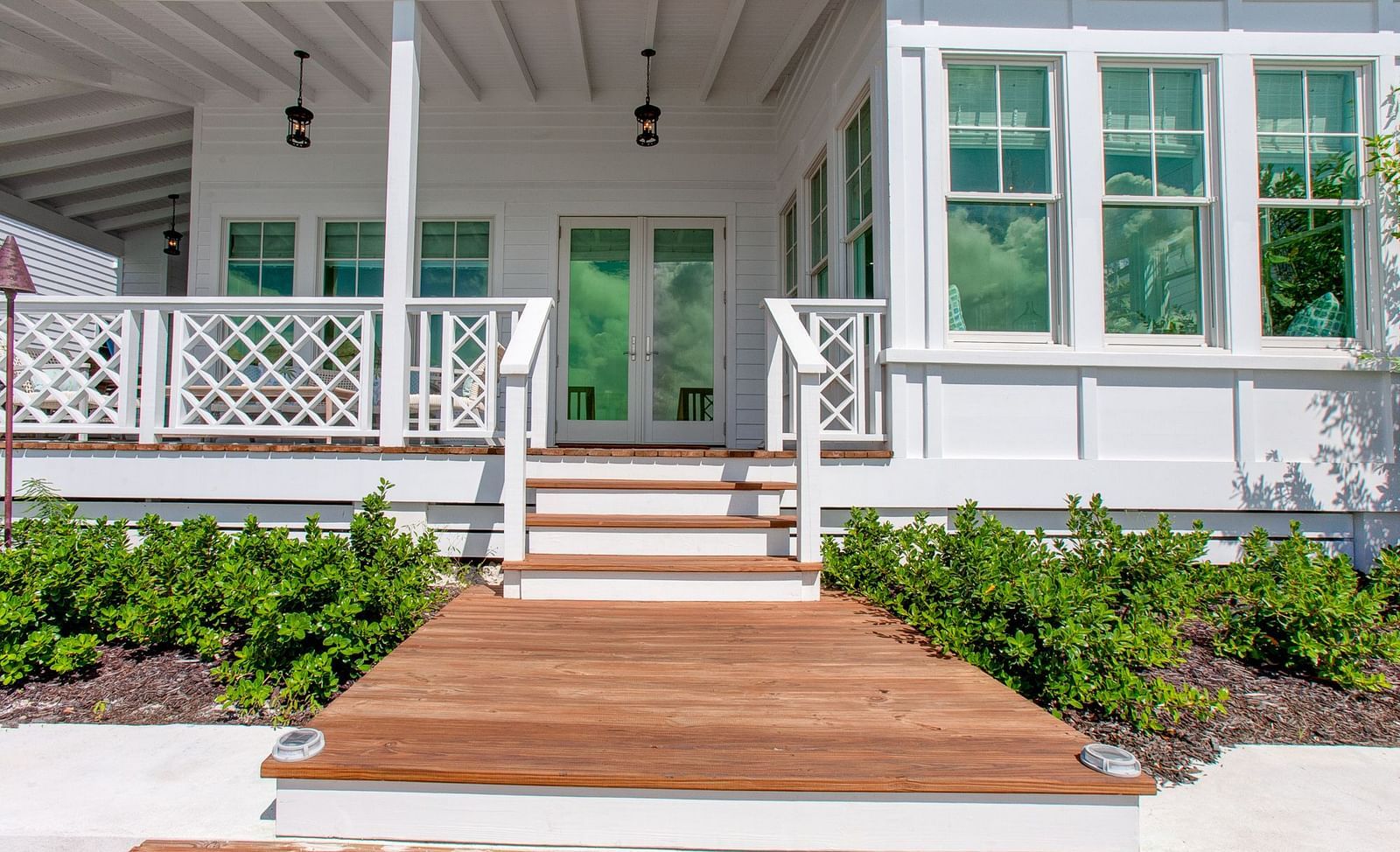 The welcoming front entrance of a Abaco Inn, featuring a wide porch with railings, stairs leading up to a wooden pathway, and well-maintained landscaping