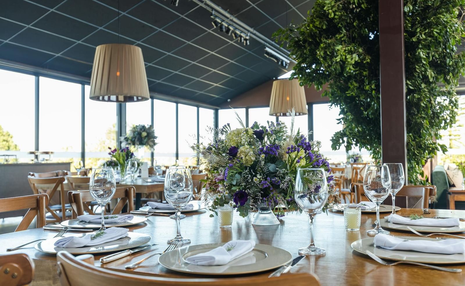 Image of a banquet hall with cutleries on the table and decorative item hanging from the ceiling.
