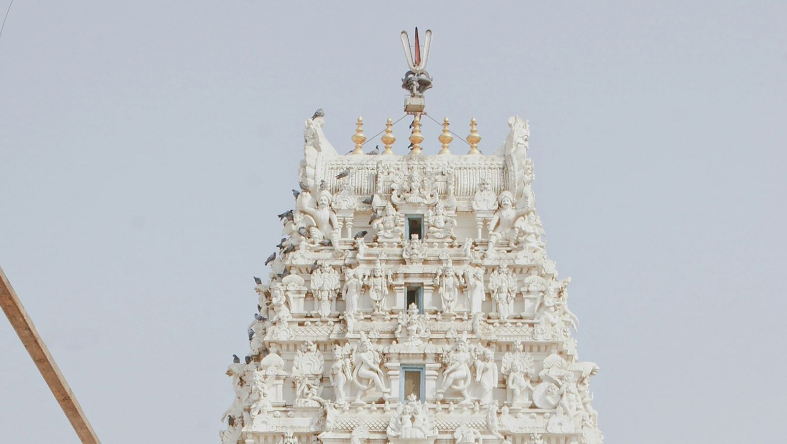 Facade image of a white temple with intricate carvings of deities on it