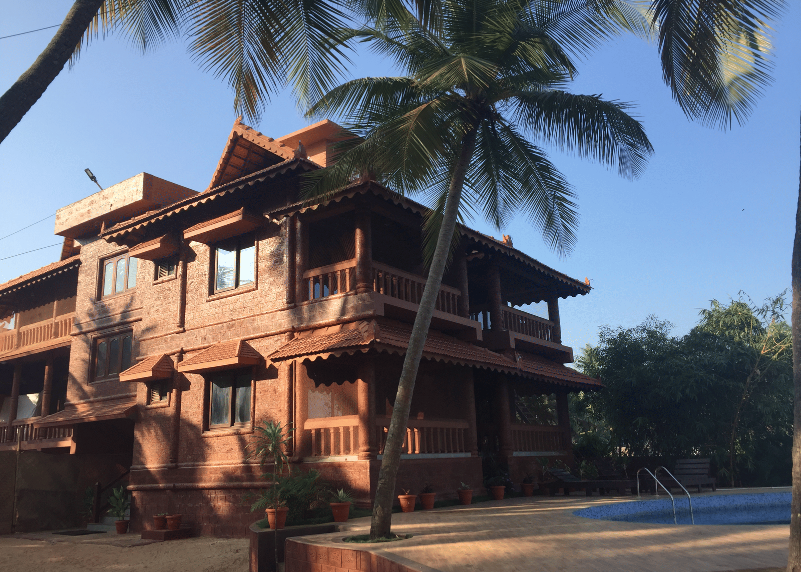 Exterior view of multi-storey Paradise Lagoon Resort featuring wooden balcony, sloped red-tiled roof, and palm trees.