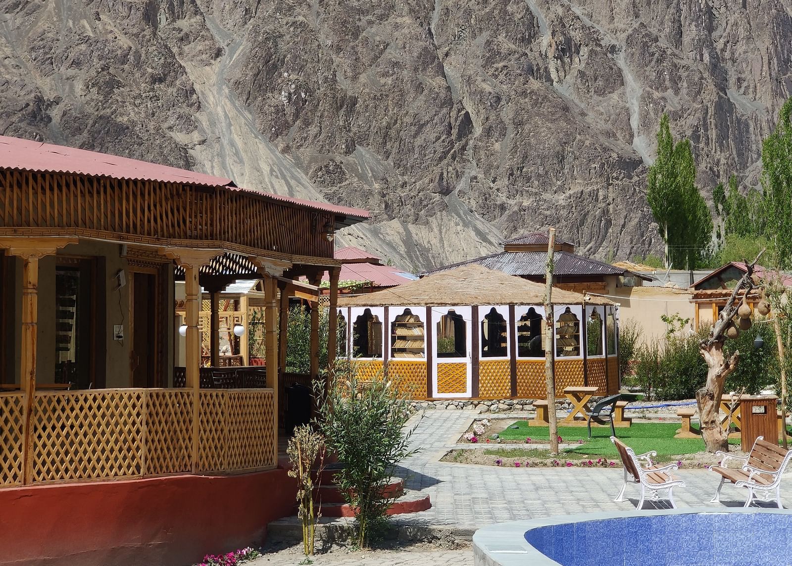 A partial view of the White Sands Resort,Ladakh highlighting the building's design and a swimming pool area with mountains in the distance.