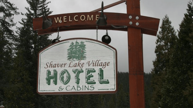 A signboard with the hotel name hanging off a wooden pole at Shaver Lake Village Hotel.