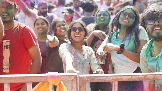 A group of friends covered in Holi colours, smiling and posing for the camera happily.