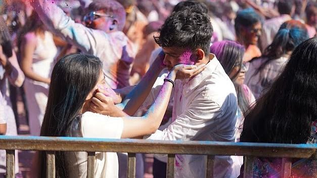 A couple smearing colours on each other’s faces while celebrating the Holi festival with joy.
