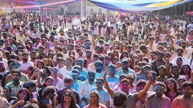 Festival-goers immersed in Holi celebrations, covered in colours, dancing, and embracing the lively spirit.