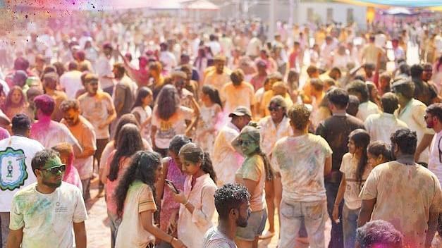 People throwing colours in the air, dancing enthusiastically, and celebrating Holi with excitement.