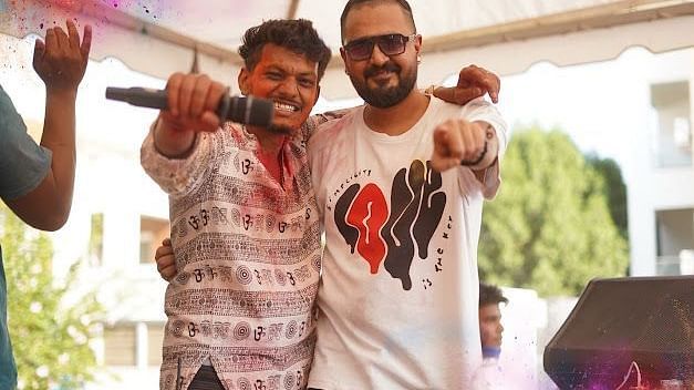 Crowd dancing and celebrating Holi under tents, with vibrant colours and energetic festival vibes.