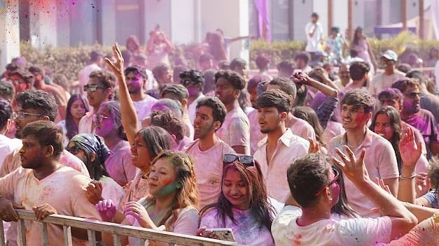 Smiling friends with faces covered in Holi colours, enjoying the Mega Holi Festival 2025.