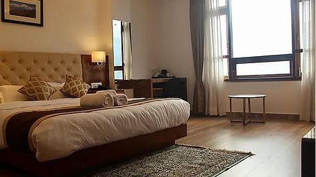 Side view of the double bed with a window in view inside Super Deluxe hill View room - Ecotel Chiminda