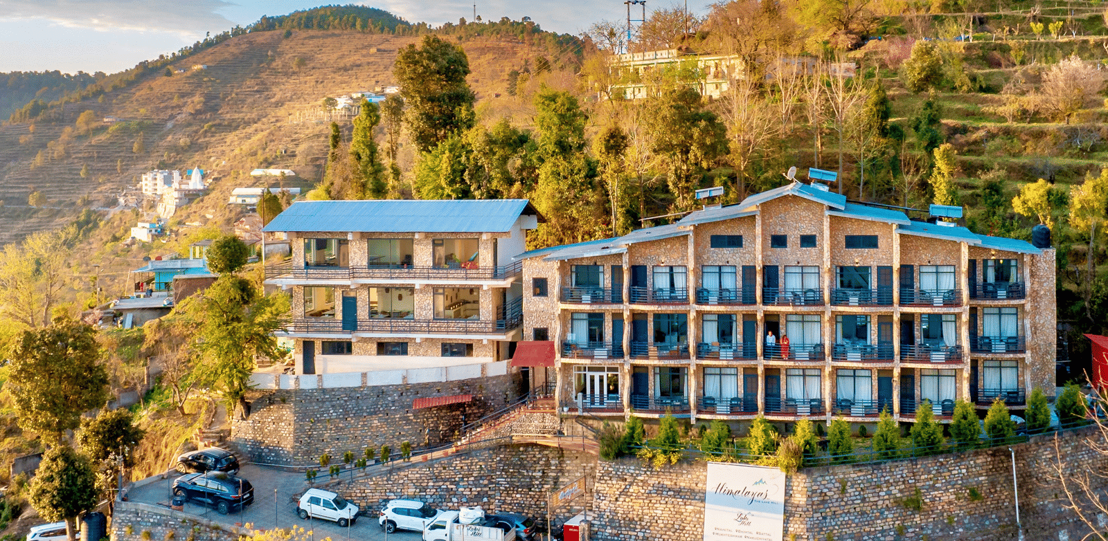 A high-angle exterior view of the Himalayas Resort By The Lake Hill, Mukteshwar building built into the side of the hill.