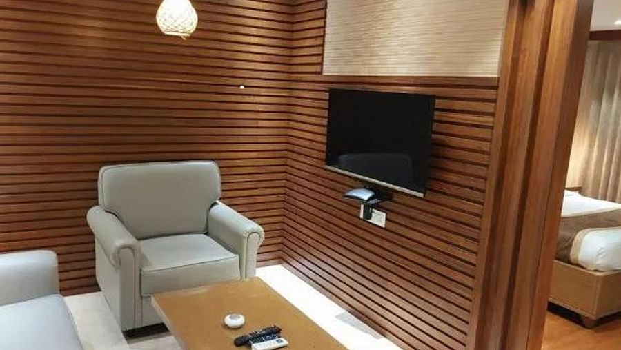 A section of a modern suite, featuring a cosy seating area with a grey sofa and a wooden coffee table, stylish shelving, and elegant lighting at Yashshree The Imperial Inn, Siliguri.