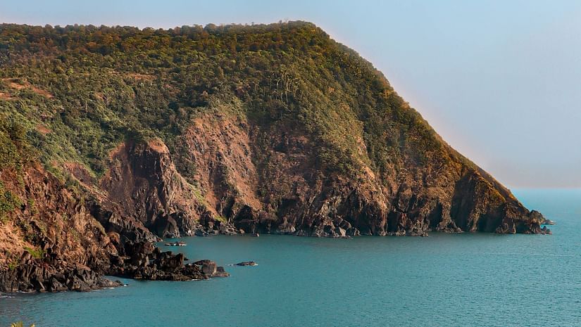 Hill-top view of Cabo de Rama Beach featuring blue ocean water  under clear blue sky