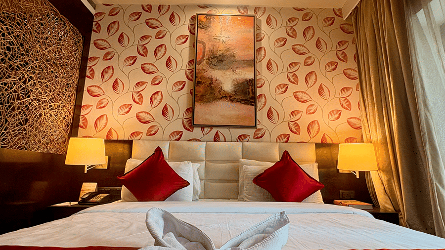 Close-up portrait view of a folded towel placed on the King-size bed with bedside tables in the Executive Suite with pattern-designed walls at Senses Hotel.