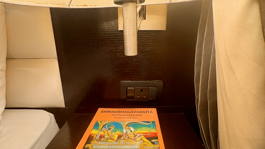 Close-up portrait shot of the SRIMAD BHAGAVADGITA book placed on a bedside table under bright lamp lighting at the Senses Hotel.