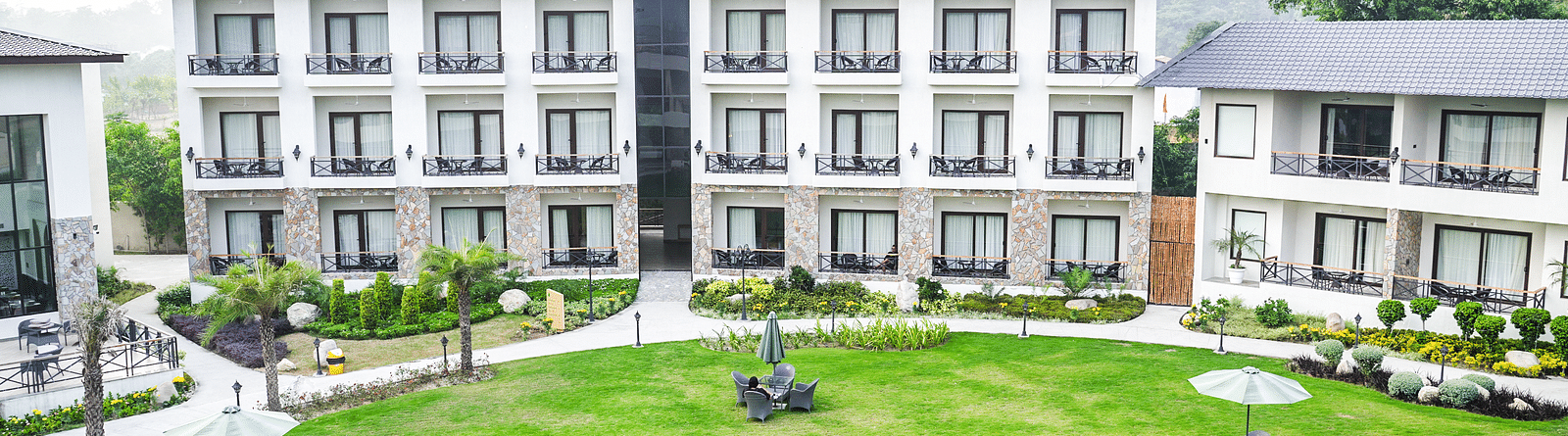 Aerial view of the resort's well-maintained lawn with outdoor seating areas, surrounded by modern guest rooms - Shervani Pebbles & Pines, Corbett