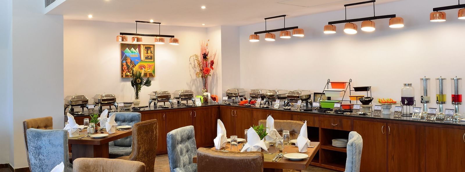 A well-lit dining area with tables and chairs, set for a meal. - Bamboo Saa Resort & Spa, Udaipur