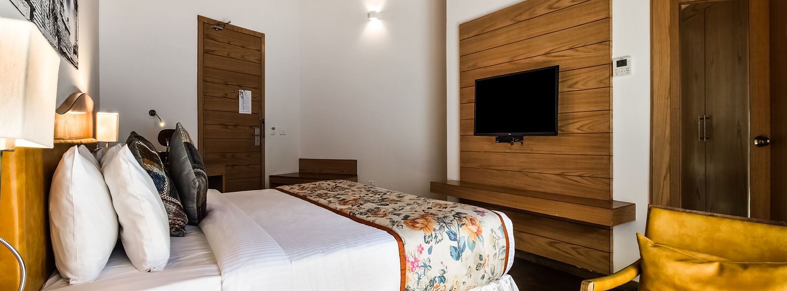 A modern bedroom with a plush bed, a mounted TV, and a armchair.- Bamboo Saa Resort & Spa, Udaipur