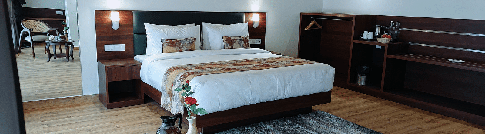 A hotel room in Darjeeling with a neatly made bed, side tables, and a patterned rug, offering a cosy and inviting feel - Sumitel JB Park, Darjeeling