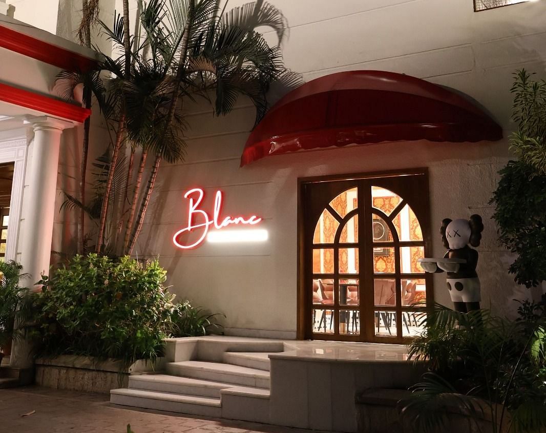 Night view of Blanc café entrance surrounded by palm trees