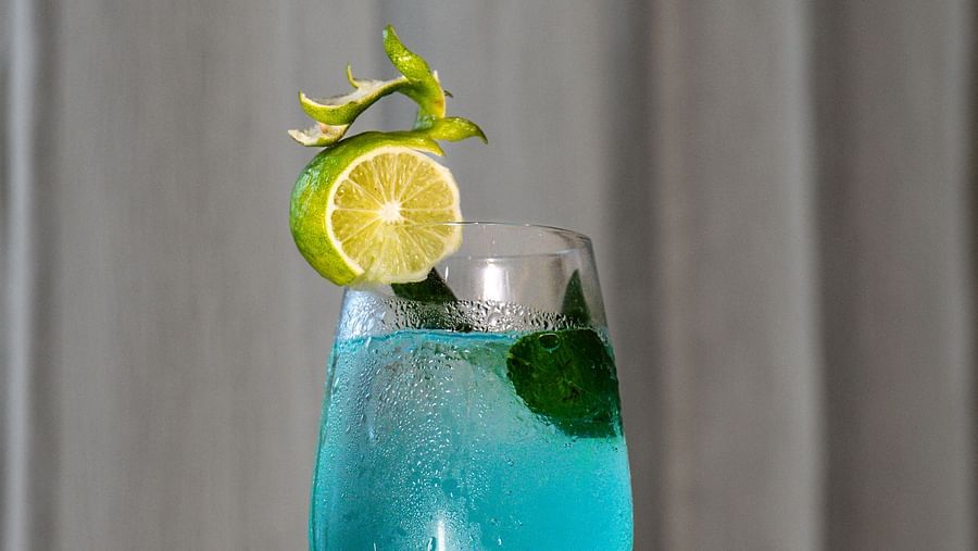 A tall glass filled with a beverage and garnished with fruit.