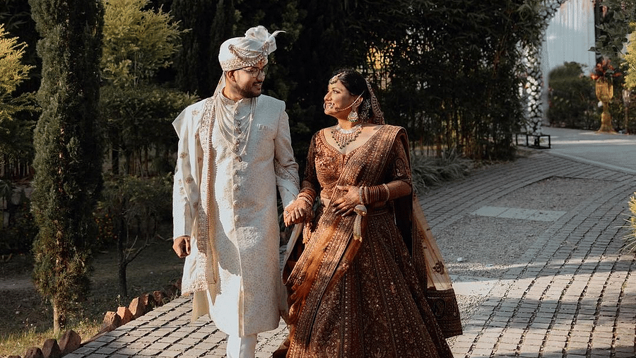 A photoshoot of a bride and groom walking on a pathway surrounded by greenery at The Sylvan Retreat, Dehradun.