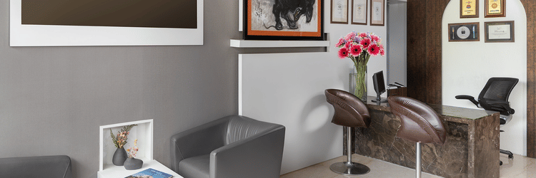 An elegant reception room at The Atara, Gurugram is furnished with comfortable seating, a large display screen, framed artwork, and a stylish full-length mirror, exuding a sophisticated feel